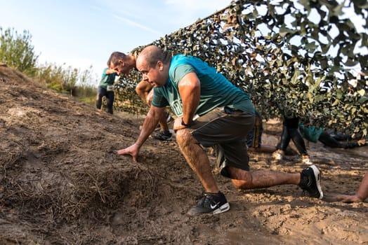 ESTARREJA, PORTUGAL - SEPTEMBER 23: Athletes crawling through mud at the Biorace on september 23, 2017 in Estarreja, Portugal.
