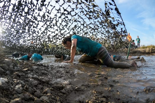 ESTARREJA, PORTUGAL - SEPTEMBER 23: Athletes crawling through mud at the Biorace on september 23, 2017 in Estarreja, Portugal.