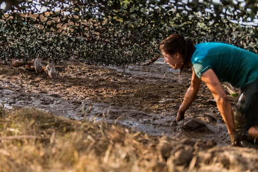ESTARREJA, PORTUGAL - SEPTEMBER 23: Athletes crawling through mud at the Biorace on september 23, 2017 in Estarreja, Portugal.