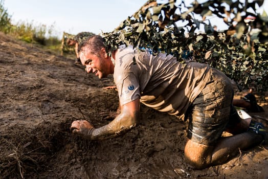 ESTARREJA, PORTUGAL - SEPTEMBER 23: Athletes crawling through mud at the Biorace on september 23, 2017 in Estarreja, Portugal.