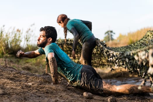 ESTARREJA, PORTUGAL - SEPTEMBER 23: Athletes crawling through mud at the Biorace on september 23, 2017 in Estarreja, Portugal.