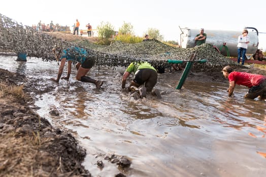 ESTARREJA, PORTUGAL - SEPTEMBER 23: Athletes crawling through mud at the Biorace on september 23, 2017 in Estarreja, Portugal.
