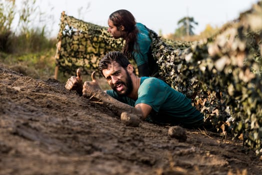 ESTARREJA, PORTUGAL - SEPTEMBER 23: Athletes crawling through mud at the Biorace on september 23, 2017 in Estarreja, Portugal.