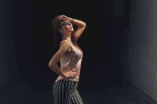 Beautiful young woman standing at the entrance to the underground garage. The model wears stylish clothes, a beige jersey, and black breeches in a white stripe. The girl is looking up, the hair is developing in the wind. Women's fashion. Urban way of life.