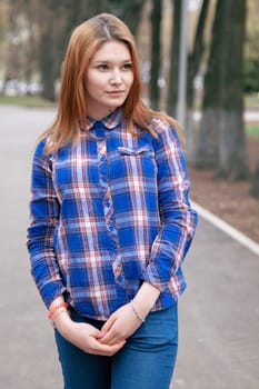 Portrait of a beautiful girl. smiling, posing on camera. in a blue shirt in a cage. On the background Wooden grid grid.