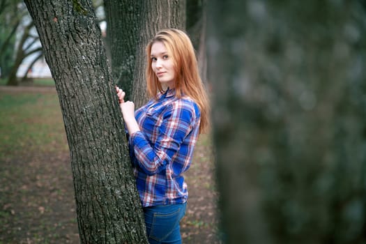 Portrait of a beautiful girl. smiling, posing on camera. in a blue shirt in a cage. On the background Wooden grid grid.