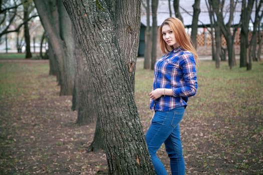 Portrait of a beautiful girl. smiling, posing on camera. in a blue shirt in a cage. On the background Wooden grid grid.