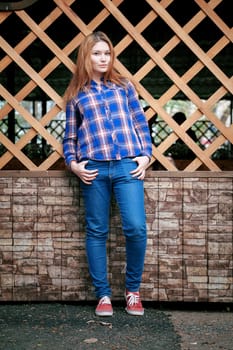 Portrait of a beautiful girl. smiling, posing on camera. in a blue shirt in a cage. On the background Wooden grid grid.