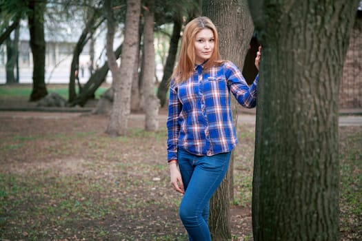 Portrait of a beautiful girl. smiling, posing on camera. in a blue shirt in a cage. On the background Wooden grid grid.