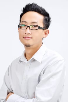 Portrait of Asian business man arms crossed, standing isolated on plain background.