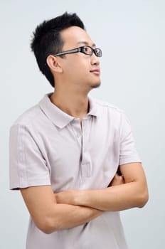 Portrait of Asian man arms crossed looking at side, standing isolated on plain background.