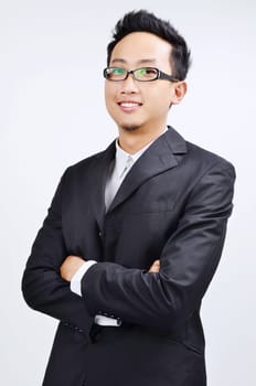 Portrait of smart Asian businessman arms crossed smiling and looking at camera, standing isolated on plain background.