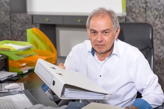 elderly man with a white shirt hands over a file folder