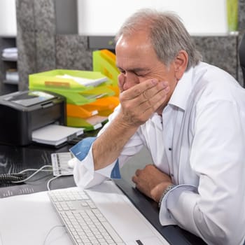 Older man sits desperately at a desk