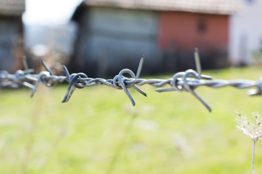 close-up the barbwire on the fence building. Blurred green background