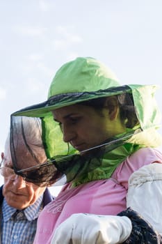 woman beekeeper looks after bees in the hive with senior beekeeper mentor