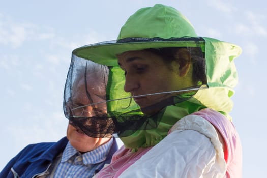 woman beekeeper looks after bees in the hive with senior beekeeper mentor