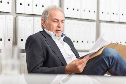 elderly man with a white shirt sitting at a desk