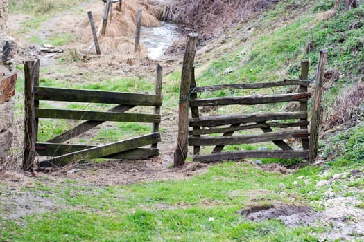 An closed gate in a wooden fence on a village road  Cloudy summer or late spring outside the city