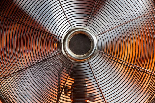 Close-up of a vintage spinning ventilator with a warm orange background