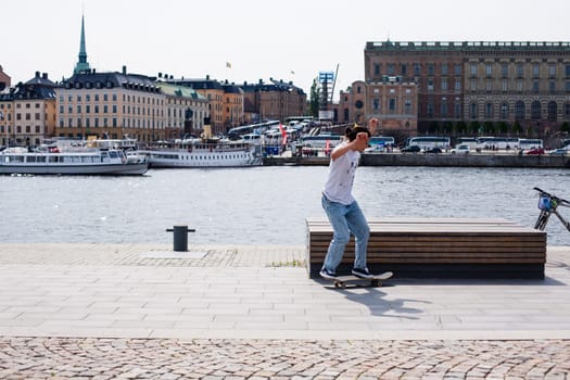 Stockholm, Sweden - June 10, 2017 : Urban life. Cool skateboarder outdoors Scandinavian guy performing a trick with his skate on the street
