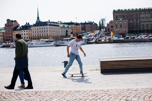 Stockholm, Sweden - June 10, 2017 : Urban life. Cool skateboarder outdoors Scandinavian guy performing a trick with his skate on the street