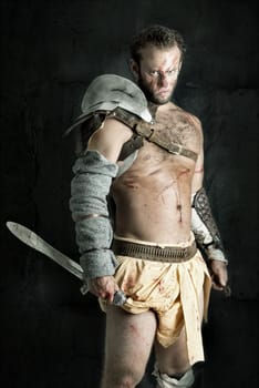 Ancient warrior or Gladiator posing against a dark background with sword