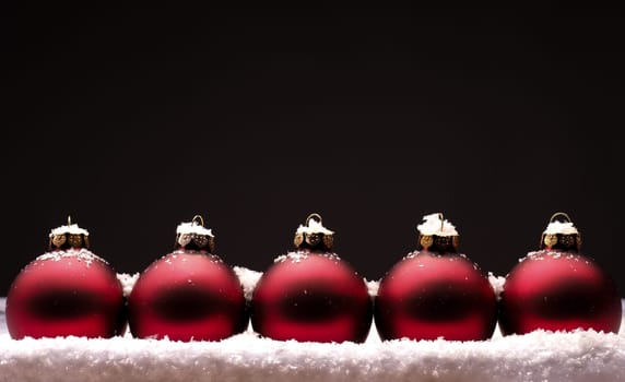 Old used red Christmas baubles with snow on a dark background
