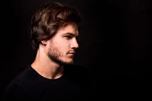 Close-up face of young bearded man on dark background modern and dramatic photo
