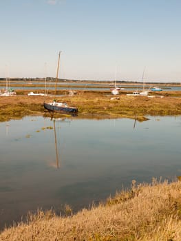 row boats parked in stream river estuary in tollesbury maldon essex  essex  england  UK