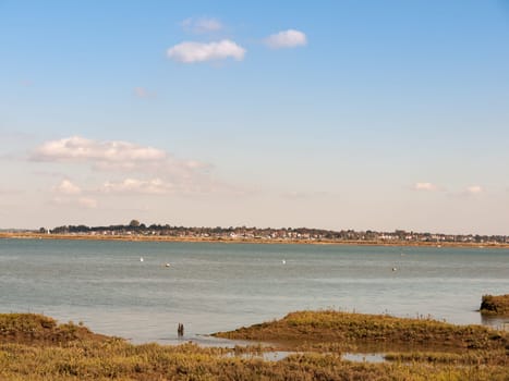 beautiful scene of river with boats grassland in front blue sky and clouds village skyline in background  essex  england  UK