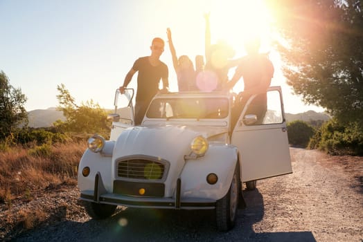 Group of happy people in a car at sunset in summer, ready for a roadtrip.