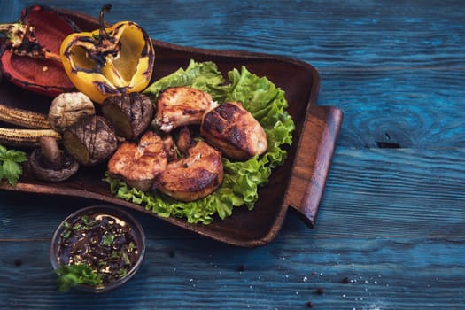 Grilled pork meat with vegetable on a blue wooden background