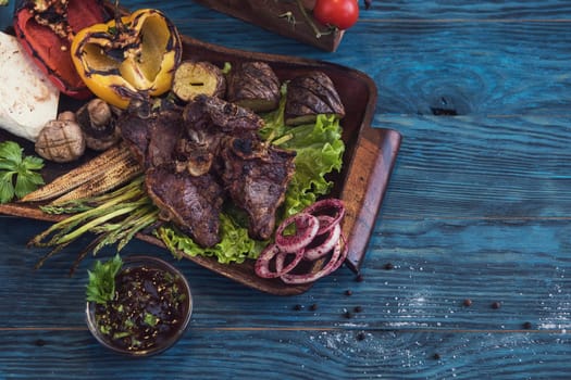 Grilled beef meat with vegetable on a blue wooden background