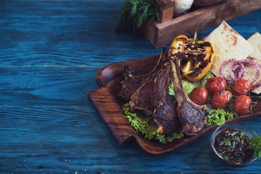 Grilled lamb meat with vegetable on a blue wooden background