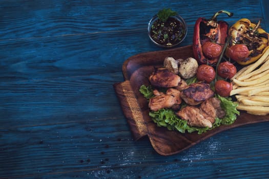 Grilled pork meat with vegetable on a blue wooden background