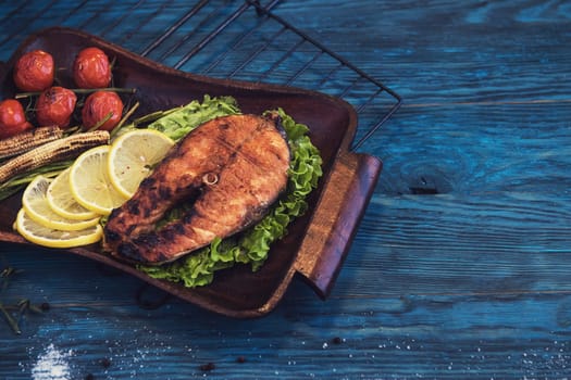 Grilled salmon steak with vegetable on a blue wooden background