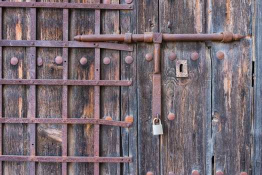 old wooden door with  wrought iron bars. Old latch wrought iron.