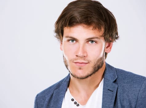 Fashion portrait of a handsome man with trendy hairstyle in a stylish jacket on light background