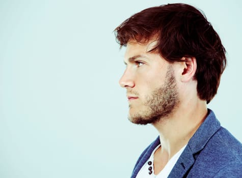 Fashion portrait of a handsome man with trendy hairstyle in a stylish jacket on light background