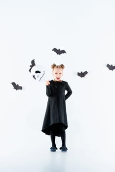 Little girl witch in black long dress and magical accessories. Halloween, the studio evening.