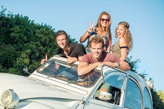 Group of happy people in a car at sunset in summer, ready for a roadtrip.