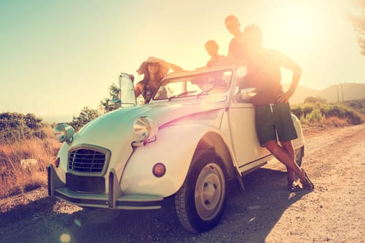 Group of happy people near a car in summertime, retro style.