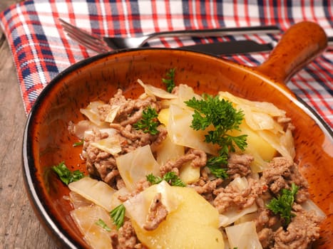 White cabbage with roasted beef and potatoes in a ceramic pan, seasonal food