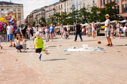 Krakow, Poland - July 29, 2017 : Children play with soap bubbles in the central square of old city. Urban life