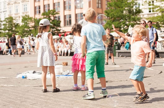 Krakow, Poland - July 29, 2017 : Children play with soap bubbles in the central square of old city. Urban life