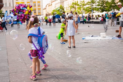 Krakow, Poland - July 29, 2017 : Children play with soap bubbles in the central square of old city. Urban life