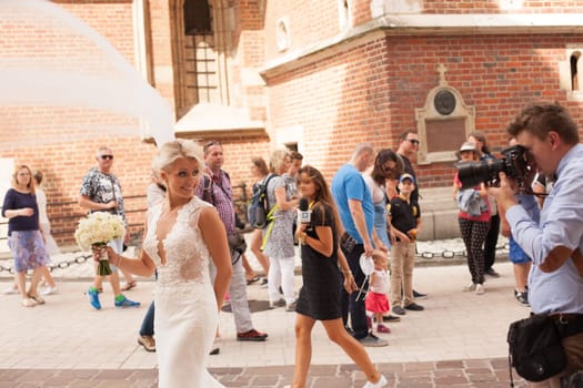 Krakow, Poland - July 29, 2017 : The photographer takes pictures of the bride in historical city, beautiful fairytale wedding