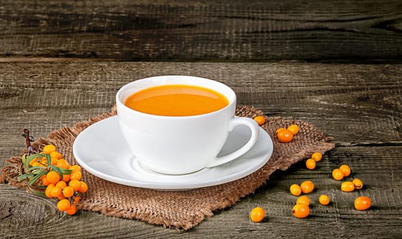 Tea of sea-buckthorn berries on wooden table with blurred background