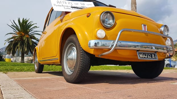 Menton, France - September 9, 2017: For Sale Sign on Windshield of Vintage Yellow Fiat 500 Car Parked on the Esplanade Francis Palmero in the City of Menton.
